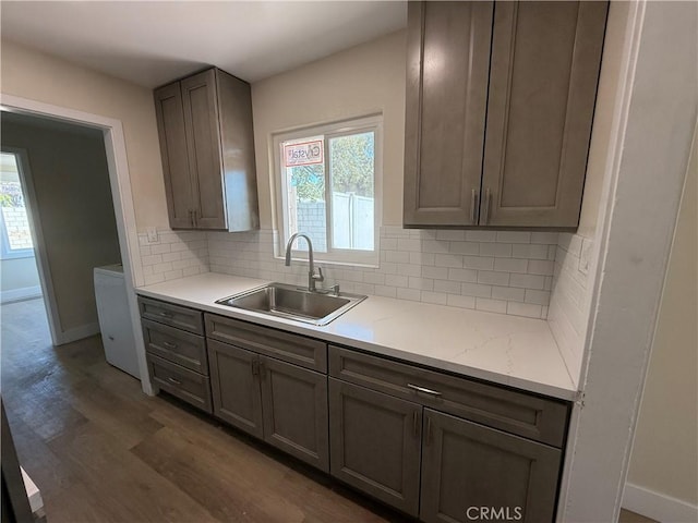 kitchen featuring a sink, decorative backsplash, baseboards, and plenty of natural light