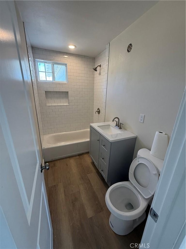 full bath featuring wood finished floors, toilet, bathtub / shower combination, and vanity