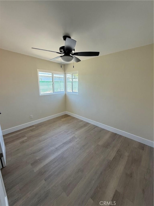 unfurnished room with wood finished floors, baseboards, and a ceiling fan