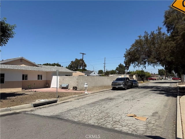 view of asphalt road with curbs and sidewalks