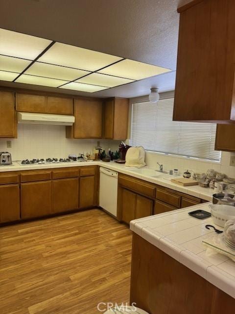 512 Via Ln, Paloma, Riverside, CA 92507 - kitchen featuring white appliances, under cabinet range hood, decorative backsplash, light wood-style floors, and brown cabinets