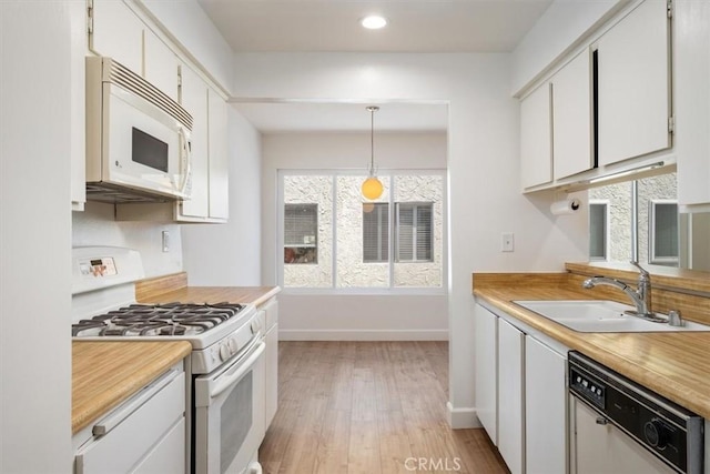 kitchen featuring white appliances, a sink, baseboards, light wood-style floors, and light countertops