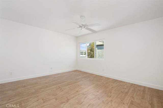 unfurnished room featuring baseboards, light wood-style flooring, and ceiling fan