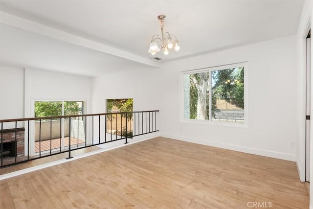 unfurnished room with a chandelier, light wood-style flooring, and baseboards