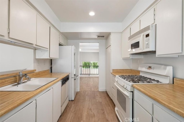 kitchen featuring white appliances, a sink, light countertops, light wood-type flooring, and white cabinets