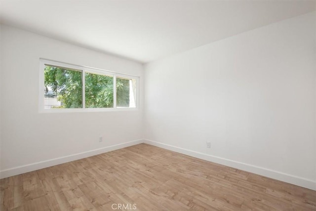 empty room with baseboards and light wood finished floors