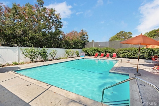 view of swimming pool featuring a patio and fence