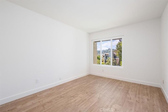 spare room featuring baseboards and light wood-type flooring
