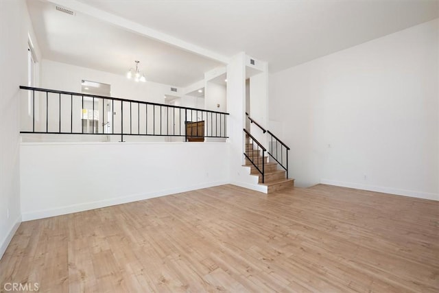 spare room with a chandelier, wood finished floors, and baseboards