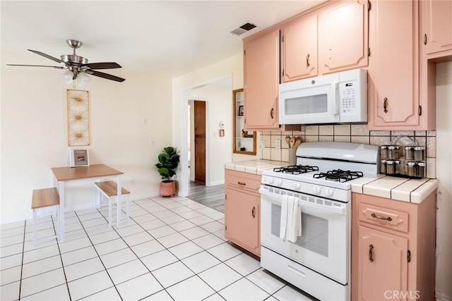 57966 El Dorado Dr, Yucca Valley, CA 92284 - kitchen featuring white appliances, tile countertops, a ceiling fan, and backsplash