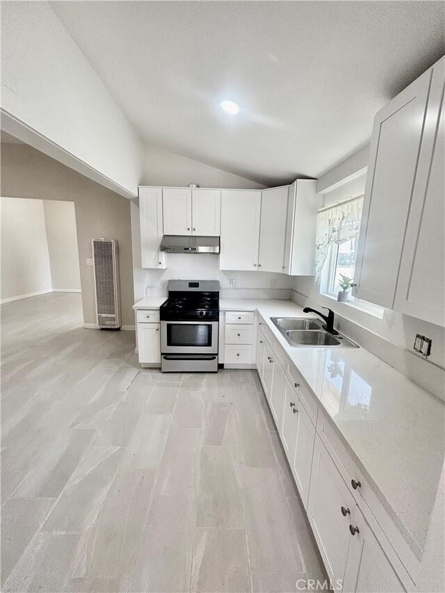 128 E 1st St, Buttonwillow, CA 93206 - kitchen with stainless steel gas stove, a sink, under cabinet range hood, lofted ceiling, and white cabinets