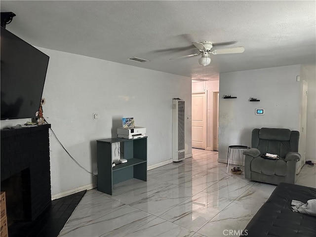 23610 David Ln Unit 1, Moreno Valley, CA 92557 - living room featuring light marble finish floors, ceiling fan, a heating unit, baseboards, and a textured ceiling