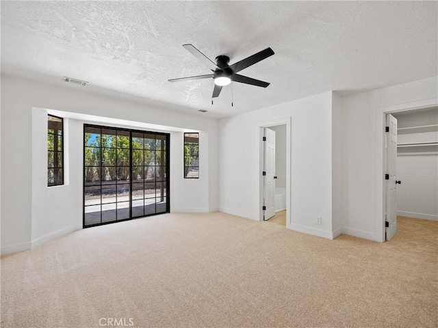 10683 El Centro Rd, Oak Hills, CA 92344 - unfurnished bedroom featuring carpet floors, a textured ceiling, baseboards, a walk in closet, and ensuite bath