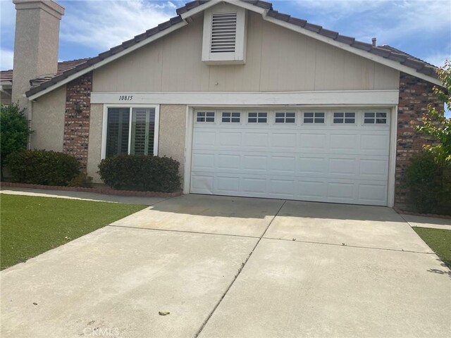 10815 Cherry Hls, Cherry Valley, CA 92223 - view of front of house featuring concrete driveway, an attached garage, a tiled roof, a chimney, and brick siding