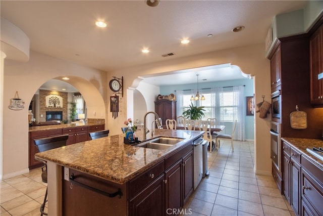 1931 James Gaynor St, Fallbrook, CA 92028 - kitchen featuring a sink, dishwasher, light tile patterned floors, arched walkways, and stone counters