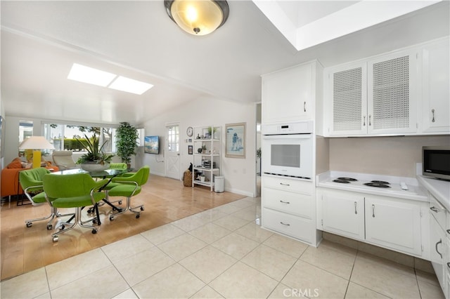 kitchen featuring white appliances, vaulted ceiling, light countertops, and white cabinetry