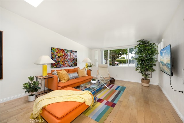 living room with light wood-style floors, baseboards, and vaulted ceiling
