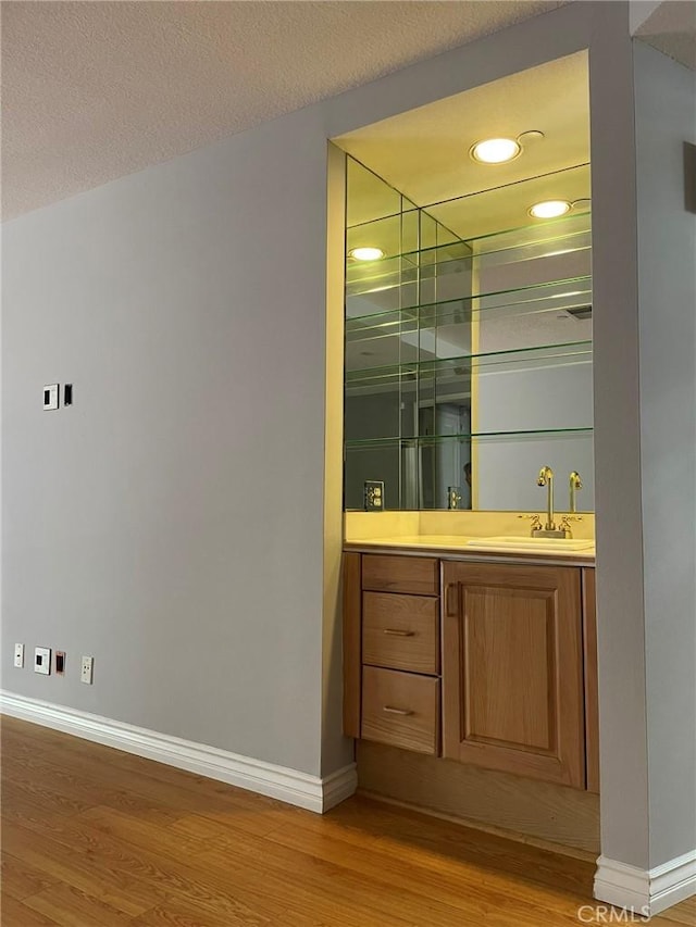 indoor wet bar featuring wood finished floors, baseboards, and recessed lighting