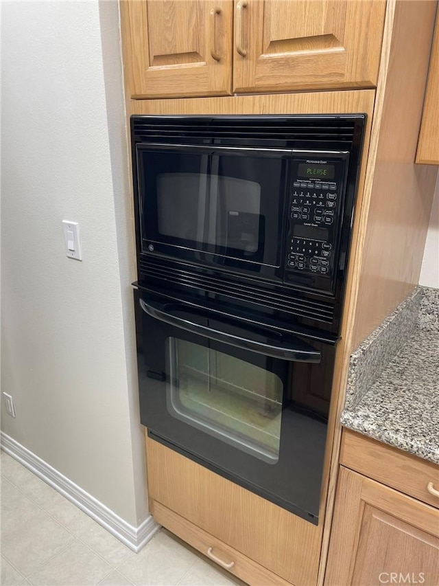 kitchen view of baseboards, black appliances, and light stone counters