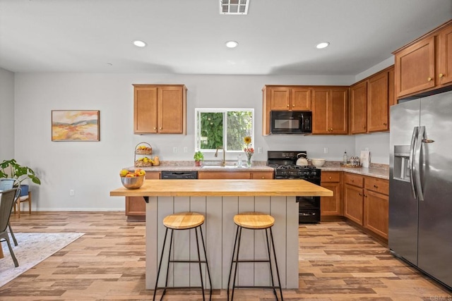 341 Dun Blazer Way, Fallbrook, CA 92028 - kitchen with black appliances, a breakfast bar, a sink, light wood-type flooring, and wooden counters