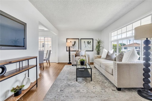 8873 Coolhurst Dr, Pico Rivera, CA 90660 - living room featuring healthy amount of natural light, a textured ceiling, wood finished floors, and baseboards