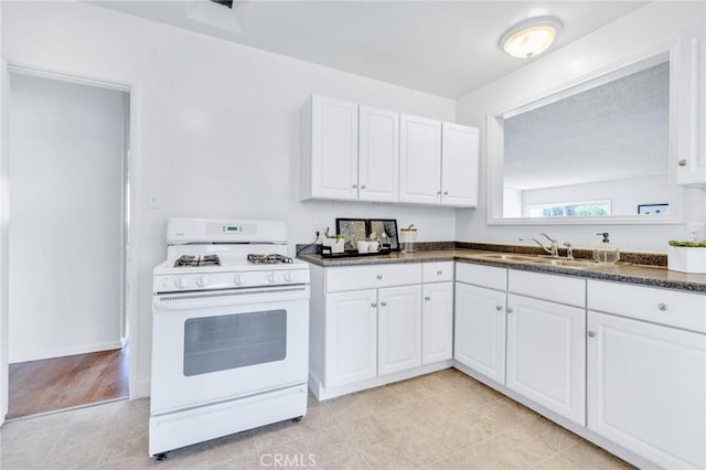 8873 Coolhurst Dr, Pico Rivera, CA 90660 - kitchen featuring white gas range, a sink, dark countertops, and white cabinets