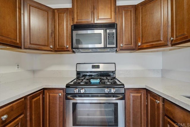 1278 E Madison Ave Unit D, El Cajon, CA 92021 - kitchen with stainless steel appliances, light countertops, and brown cabinetry
