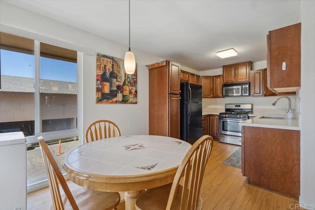 1278 E Madison Ave Unit D, El Cajon, CA 92021 - kitchen with stainless steel appliances, brown cabinetry, light wood finished floors, light countertops, and pendant lighting
