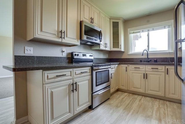 4379 Albatross Way, Oceanside, CA 92057 - kitchen featuring stainless steel appliances, cream cabinetry, light wood finished floors, glass insert cabinets, and dark stone countertops