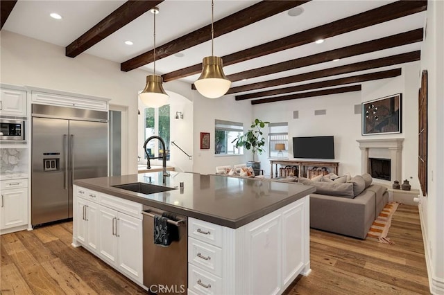737 35th St, Manhattan Beach, CA 90266 - kitchen featuring built in appliances, a sink, light wood-style flooring, dark countertops, and pendant lighting