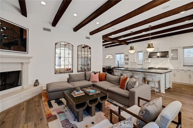 737 35th St, Manhattan Beach, CA 90266 - living room with recessed lighting, light wood finished floors, a fireplace with raised hearth, a chandelier, and beamed ceiling