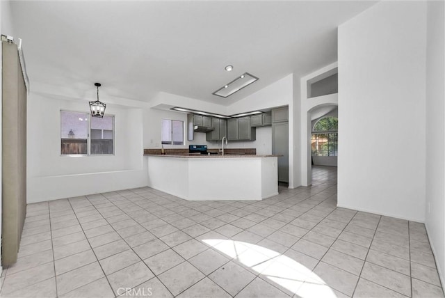 12820 Pan Am Blvd, Moreno Valley, CA 92553 - kitchen with a peninsula, light tile patterned floors, vaulted ceiling, arched walkways, and a sink