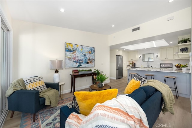 living area featuring recessed lighting, light wood-style flooring, and baseboards