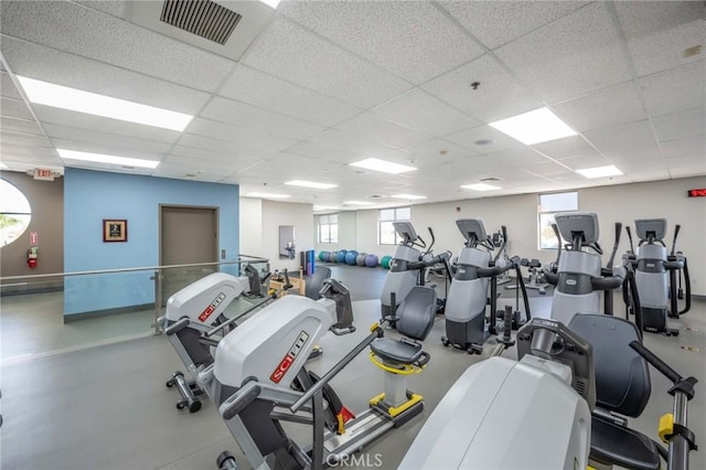 workout area with a paneled ceiling and baseboards