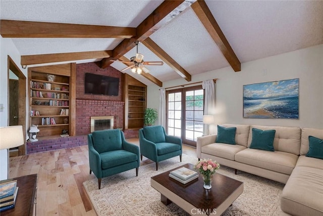living area featuring wood finished floors, a ceiling fan, built in shelves, a brick fireplace, and a textured ceiling