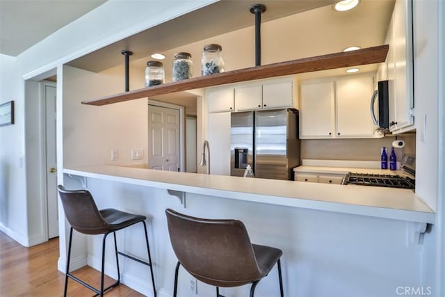 111 Greenfield, Irvine, CA 92614 - kitchen with stainless steel appliances, light countertops, a peninsula, baseboards, and light wood finished floors