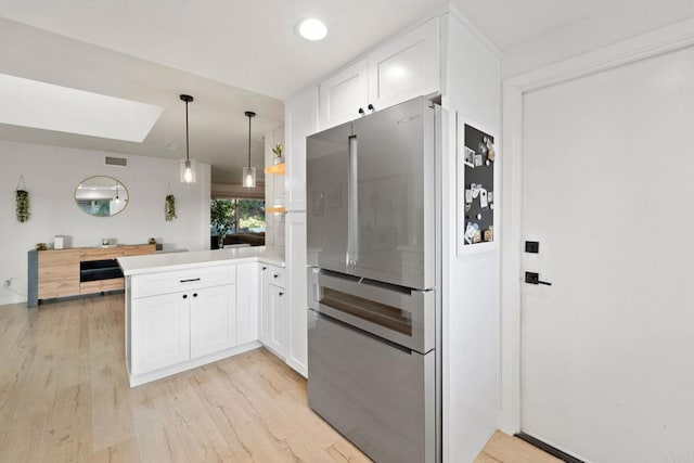 7325 Conestoga Ct, San Diego, CA 92120 - kitchen featuring freestanding refrigerator, a peninsula, a skylight, light wood-type flooring, and white cabinetry