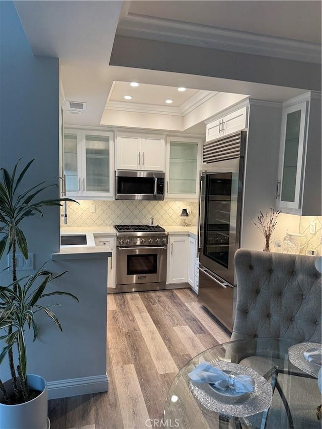 28185 Via Luis, Laguna Niguel, CA 92677 - kitchen with high end appliances, a tray ceiling, crown molding, light countertops, and backsplash
