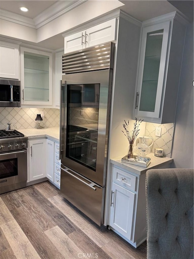28185 Via Luis, Laguna Niguel, CA 92677 - kitchen with stainless steel appliances, light countertops, crown molding, wood finished floors, and glass insert cabinets