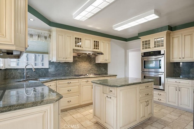 338 S La Serena Dr, West Covina, CA 91791 - kitchen featuring stainless steel appliances, a sink, under cabinet range hood, tasteful backsplash, and cream cabinetry