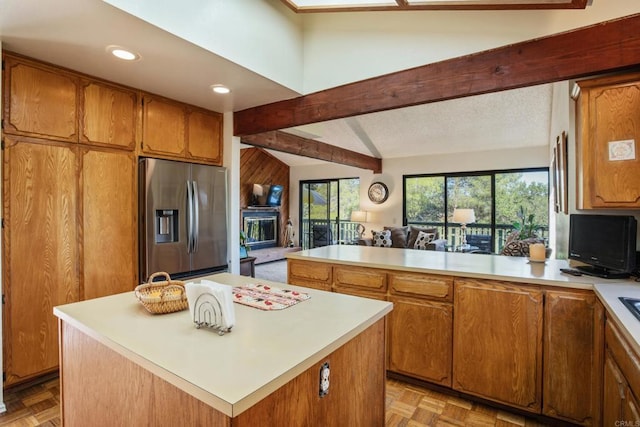 28330 Meadow Glen Way W, Escondido, CA 92026 - kitchen featuring stainless steel fridge, light countertops, a fireplace with raised hearth, a peninsula, and brown cabinetry