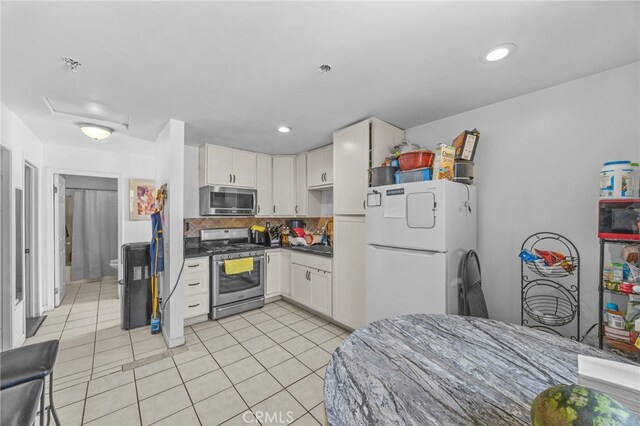 1709 S Townsend St, Santa Ana, CA 92704 - kitchen with stainless steel appliances, light tile patterned floors, dark countertops, backsplash, and white cabinets