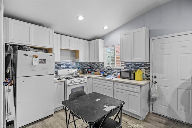 1709 S Townsend St, Santa Ana, CA 92704 - kitchen with white appliances, a sink, vaulted ceiling, backsplash, and white cabinetry