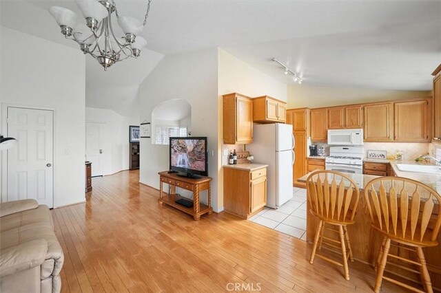 28613 Apricot Pl, Valencia, CA 91390 - kitchen with white appliances, high vaulted ceiling, a sink, a chandelier, and light wood-type flooring