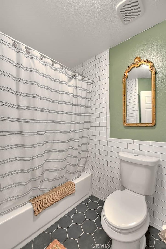 13023 Avenida Empresa, Riverside, CA 92503 - full bathroom featuring shower / bathtub combination with curtain, tile patterned floors, tile walls, a textured ceiling, and wainscoting