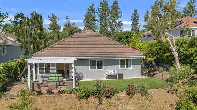 rear view of house with a yard and stucco siding