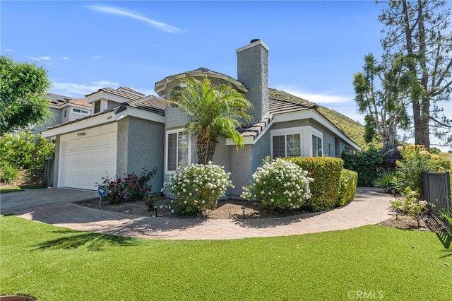 view of side of home with a garage, a chimney, stucco siding, and a tiled roof