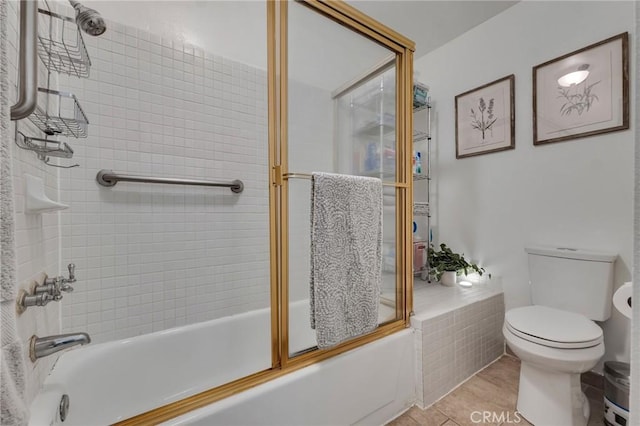 full bathroom featuring toilet, combined bath / shower with glass door, and tile patterned flooring