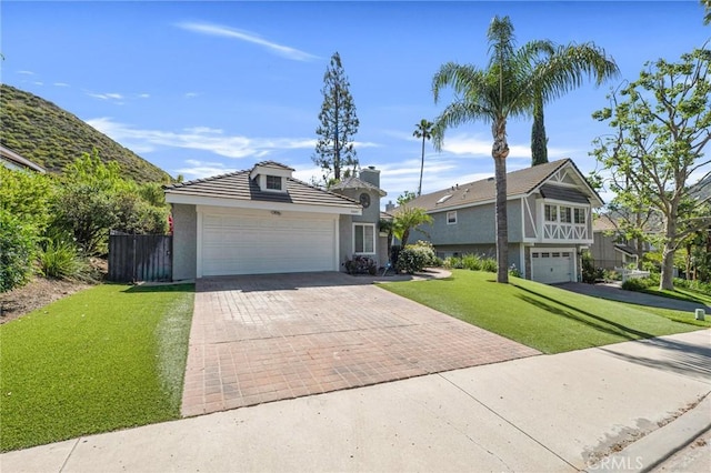 view of front facade featuring decorative driveway, a front yard, stucco siding, and a garage