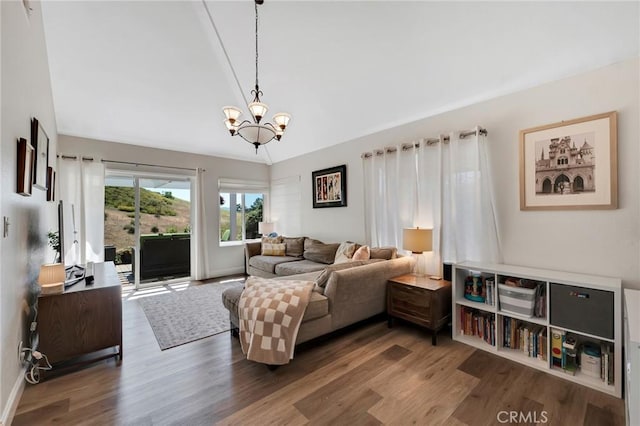 living area featuring a chandelier, wood finished floors, baseboards, and lofted ceiling